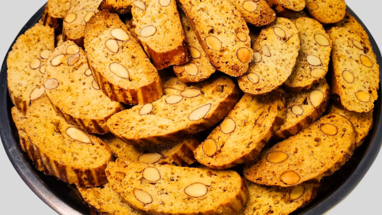 شرائح من البسكوت الإيطالي المقرمش مزينة بشرائح اللوز، مرتبة على طبق معدني مزخرف. التعليق: شرائح بسكوت إيطالي لذيذة مع اللوز، تقدم كوجبة خفيفة مثالية مع القهوة.