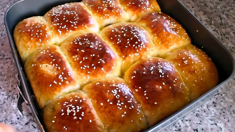 تظهر الصورة خبز البريوش الطري بعد خبزه في صينية مستطيلة على سطح رخامي. يمتاز بلونه الذهبي اللامع ومظهره الجذاب مع رشات السمسم التي تضيف نكهة مميزة.