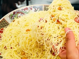 طبق شعيرية تقليدي يحتوي على خيوط رفيعة من الشعيرية المصفوفة على طبق مزخرف بنقوش شرقية، مع أيدي تلتقط الشعيرية.