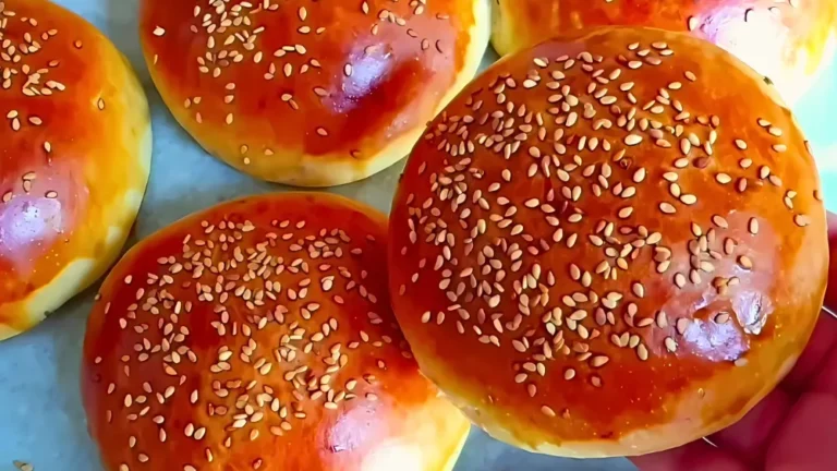 مجموعة من قطع الخبز الطرية المغطاة بطبقة لامعة مع حبات السمسم.