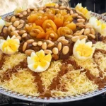 طبق مغربي من السفة المدفونة بالدجاج مزين بشرائح المشمش، اللوز المحمص، والبيض المسلوق، مع خطوط من القرفة.