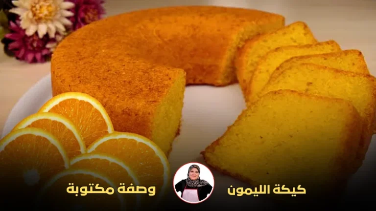 كيكة الليمون المستديرة مع شرائح برتقال مزينة في المقدمة وزهور ملونة في الخلفية.