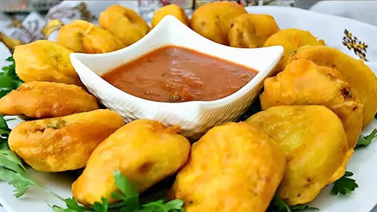 طبق من البطاطا المقلية الذهبية محشوة، مرتبة حول صحن صغير يحتوي على صلصة الطماطم الحمراء، مع بعض أوراق البقدونس للتزيين.