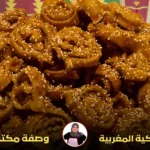 طبق مليء بالشباكية المغربية الذهبية المزينة بالسمسم، مع خلفية ملونة بنقوش تقليدية مغربية.