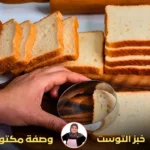 يد تستخدم أداة دائرية لتقطيع شرائح خبز التوست الأبيض.
