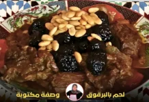 طبق مغربي تقليدي يحتوي على لحم مطهو مع البرقوق المجفف واللوز المحمص، مقدم على طبق مزخرف بزخارف شرقية.